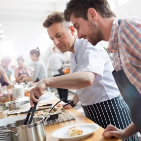 zwei Männer stehen zusammen am Herd und kochen