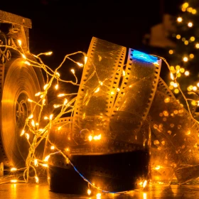 Filmrolle mit Lichterkette angeleuchtet, Weihnachtsbaum im Hintergrund