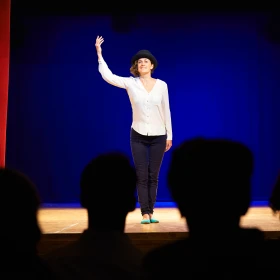 Frau führt eine Aufführung auf der Bühne vor