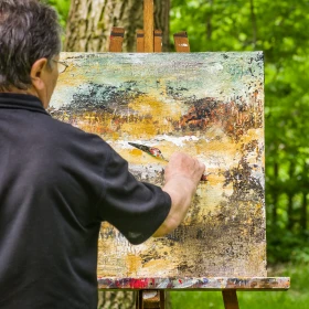 Mann mal Bild auf einer Staffelei in der Natur