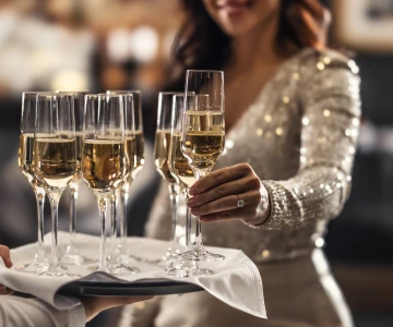 Frau greift ein Glas Sekt vom Tablett