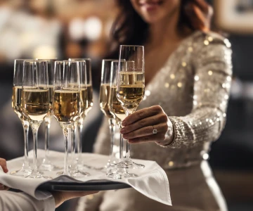 Frau greift ein Glas Sekt vom Tablett