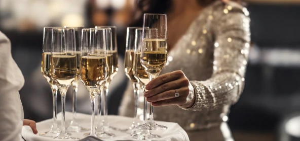 Frau greift ein Glas Sekt vom Tablett