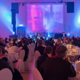 Personen sitzen an Tischen und warten bis das Abendprogramm beginnt