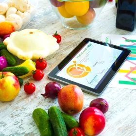 Obst und Gemüse auf einem Tisch neben einem Tablet