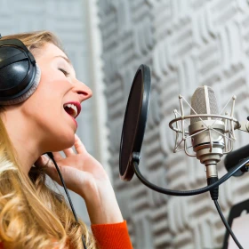 Singende Frau in einem Tonstudio vor einem Aufnahmegerät