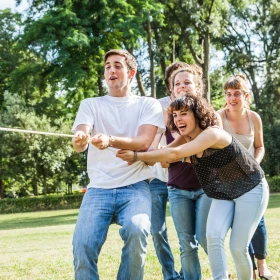 Personen ziehen gemeinsam an einem Seil und haben Spaß