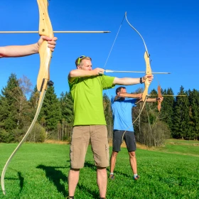 Personen stehen in Reihe und schießen mit Pfeil und Bogen