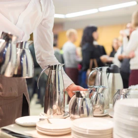 Kellnerin bringt Kaffeekannen an einen Tisch