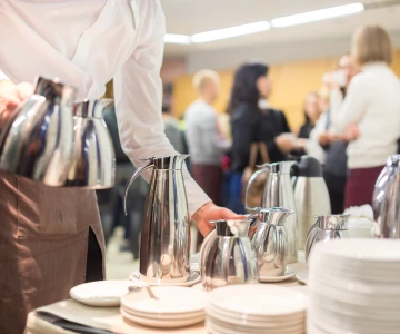 Kellnerin bringt Kaffeekannen an einen Tisch