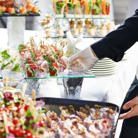 Person bereitet Buffet vor und stellt Essen auf eine Glasplatte