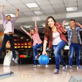 Frau beim Werfen einer blauen Bowlingkugel