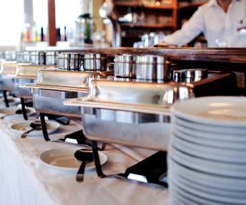 Buffet mit verschiedenen Chafings, geschlossen, Kellner im Hintergrund