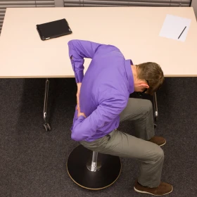 Person massiert sich den unteren Rücken in einer Übung