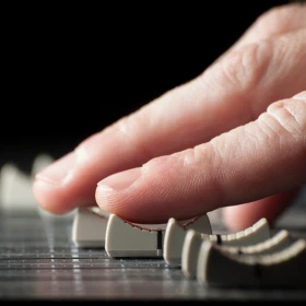 Eine Hand bedient ein Mischpult