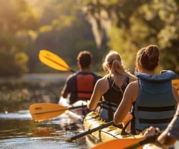 3 Personen im Kanu fahren einen Fluss hinunter, gelbe Kanus, blaue Schwimmweste, Gelbe Paddel