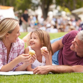 Familie sitzt auf der Wiese und isst Eis