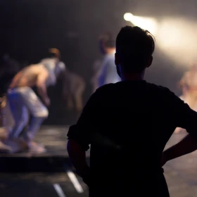 Person schaut von der Seite einer Aufführung zu