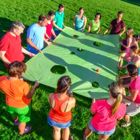 Gruppe hält gemeinsam eine Plane fest und versucht das Spiel zu lösen