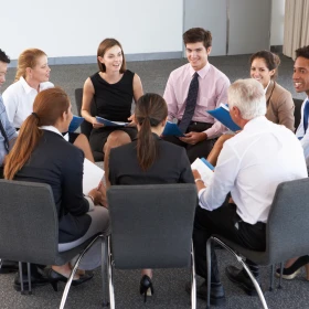 Menschen sitzen in einem Sitzkreis in einer Besprechung