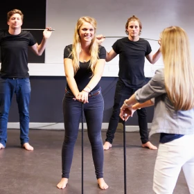 mehrere Personen üben mit einem Stock die Choreo