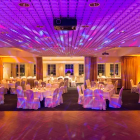 Raum mit gededeckten Tischen und Stühle mit Hussen