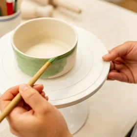 Person bemalt ihre Schüssel mit grüner Farbe