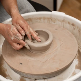 Person formt eine Schale auf einem Töpferteller