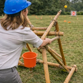 Eine Frau mit blauem Helm schießt mit einem Katapult auf eine Zielscheibe