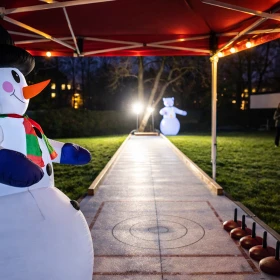 Mobile Eisstockbahn auf einer Wiese mit rotem Zelt und weihnachtlicher Dekoration