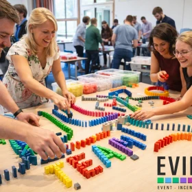 Mitarbeiter haben bei einem Domino-Workshop das Wort TEAM als Kettenreaktion aus verschiedenen farbigen Dominosteinen gelegt