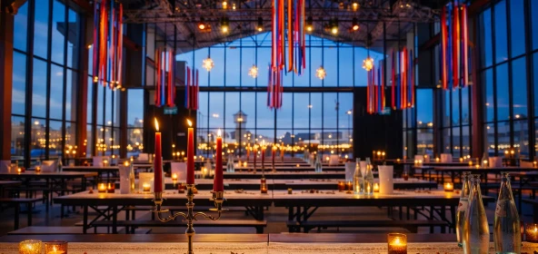 Eine stilvoll dekorierte Eventlocation im orientalischen Stil mit farbenfrohen Stoffbahnen, warmem Kerzenlicht und atmosphischer Beleuchtung. Die Kombination aus moderner Architektur und orientalischen Elementen schafft eine einzigartige Kulisse für eine exklusive Firmenfeier.