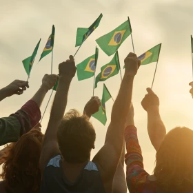 Menschengruppe hält brasilianische Flaggen nach oben und schaut in den Himmel
