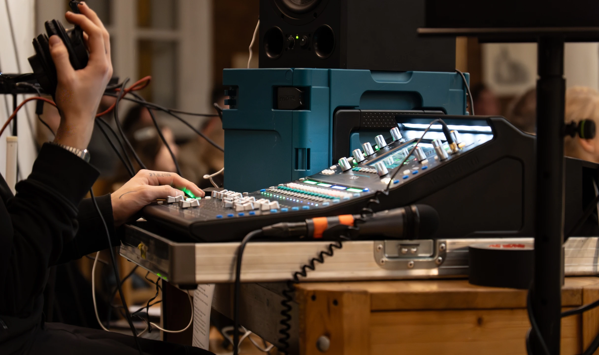 Person steuert den Ton im Hintergrund über ein Mischpult