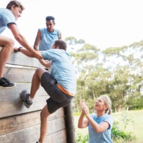 Personen helfen sich gegenseitig um über die Wand zu klettern