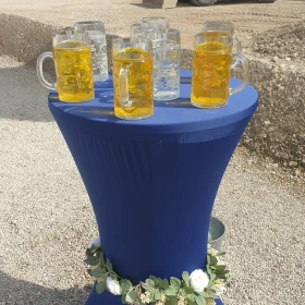 Bierkrüge auf einem Stehtisch mit blauer Husse