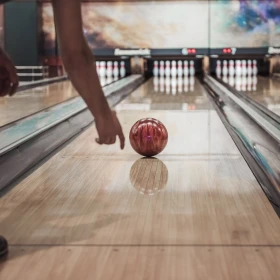 Person wirft Bowlingkugel die Bahn hinter