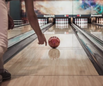 EVINTA_Bowling Firmenfeier_Bild01 Person wirft Bowlingkugel die Bahn hinter
