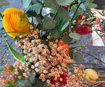 EVINTA_Floristikworkshop_Bild 01 Blumenstrauß in einer Hand, Gelbe Ranunkel, Tulpen in verschiedenen Farben,
Eukalyptus, Statice oder getrocknetes Schleierkraut, Rote Nelken