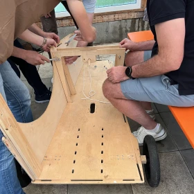 Drei Personen bauen eine Seifenkiste zusammen