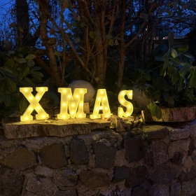 leuchtender X-Mas Schriftzug auf einer Steinmauer