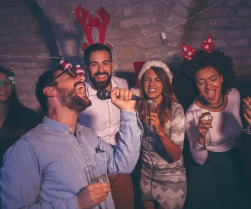 Personen singen gemeinsam einen Karaoke Song mit weihnachtlichen Mützen