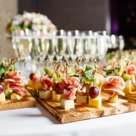 Canapés im Vordergrund, Sektgläser im Hintergrund, Buffet