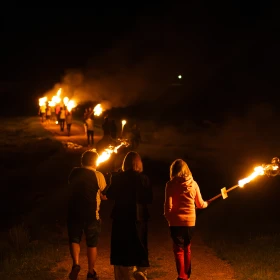 Menschengruppe macht eine Fackelwanderung durch die Dunkelheit