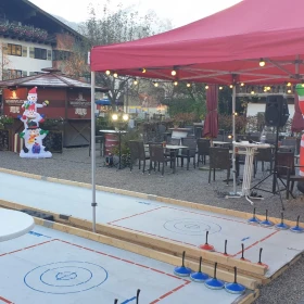 Mobile Eisstockbahn mit roten Pavillon überdacht 
weihnachtliche Dekoration