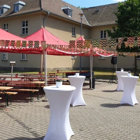 EVINTA_Firmen Sommerfest auf Ihrem Betriebsgelände_Bild02 Bierzeltgarnituren unter einem roten Pavillon, Wimpelkette, Stehtische mit weißen Hussen