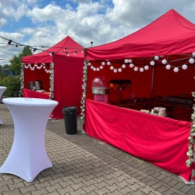 Markstände, rote Pavillons, sommerliche Dekoration, Stehtische