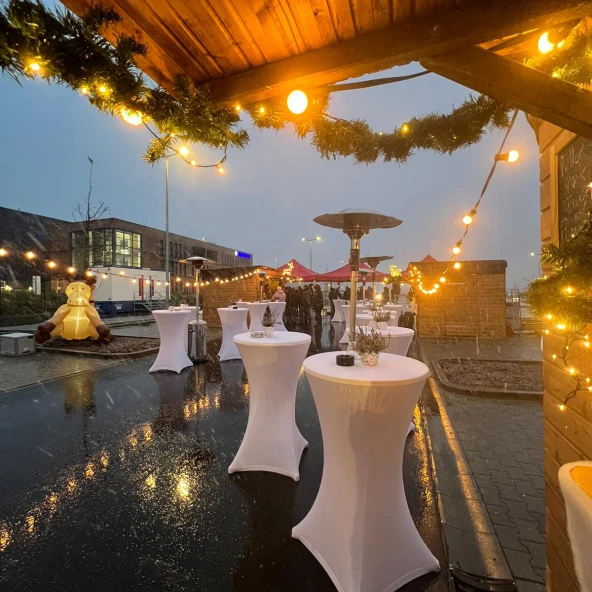 Weihnachtsmarkt mit Holzhütten und weißen Stehtischen