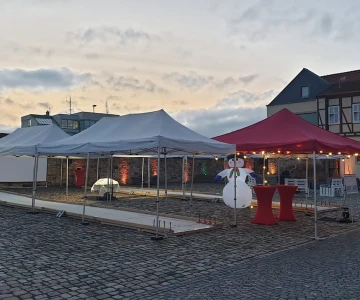 Eisstockbahn im Außenbereich, Schneemann als Deko, rote Pavillons