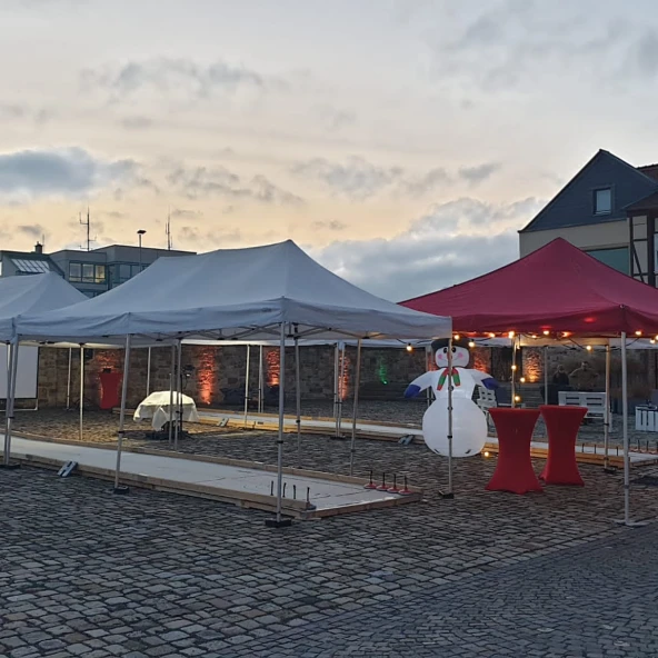 Eisstockbahn im Außenbereich, Schneemann als Deko, rote Pavillons